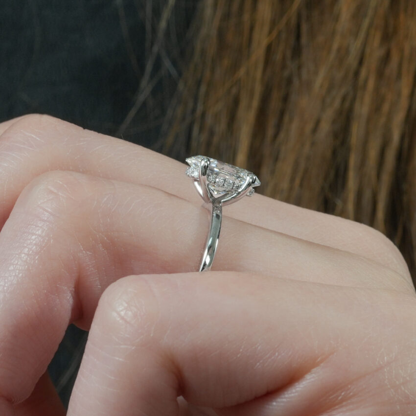 Angle view of ultra low hidden halo engagement ring in lifestyle