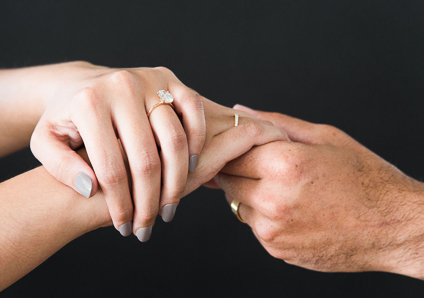 two people holding hands in a dainty manner with oval engagement ring on female