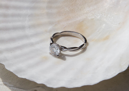 white gold engagement ring resting inside of a cream colored flat seashell