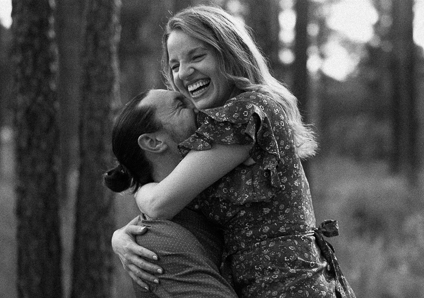 man lifting woman while both laugh and embrace