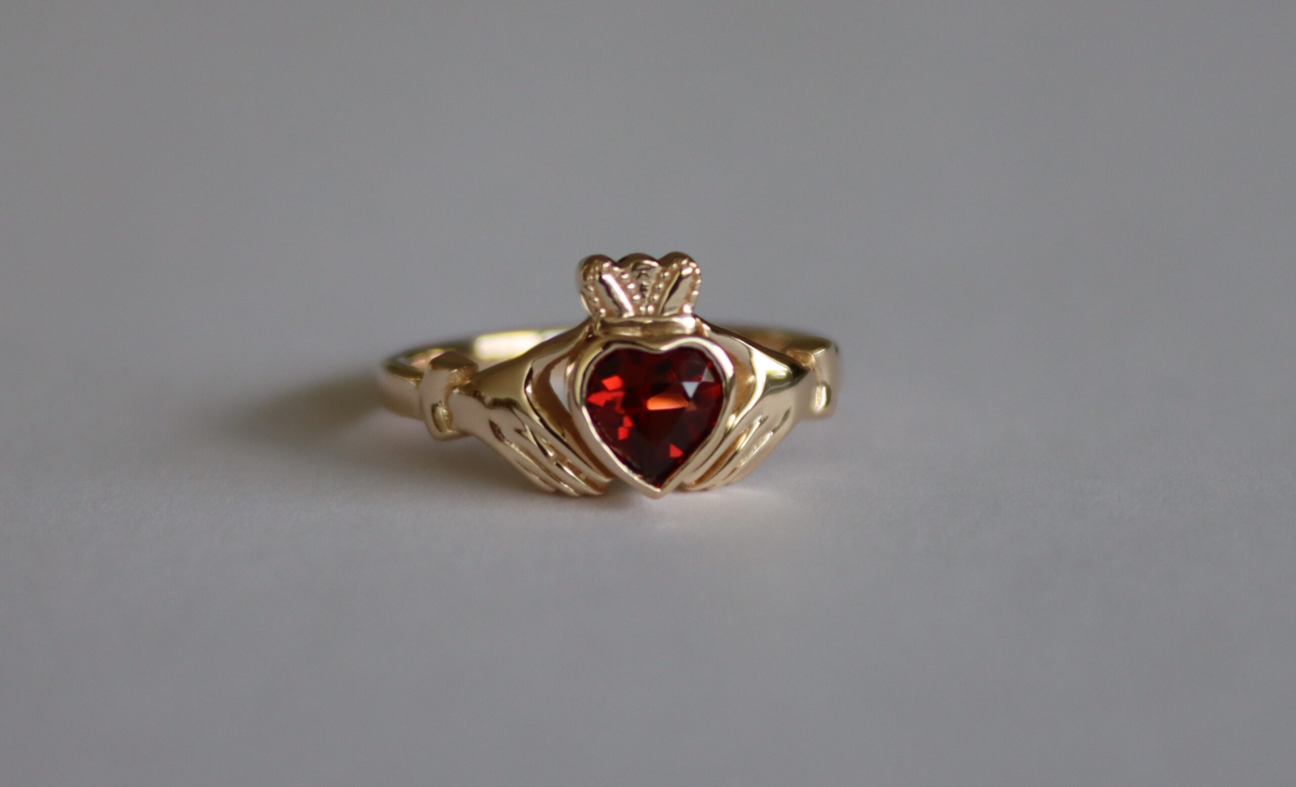 Custom garnet irish claddagh ring in yellow gold