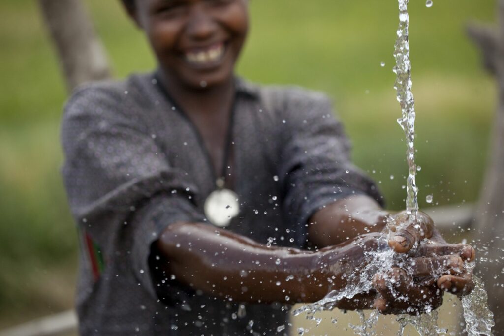 Charity Water well pouring clean water to wash hands