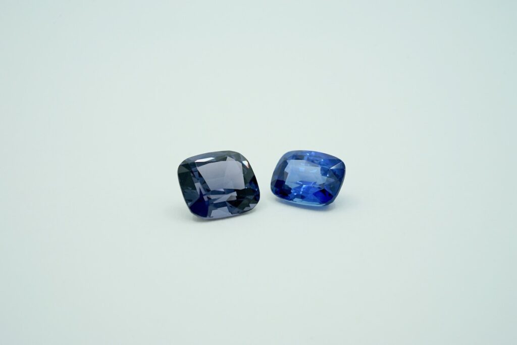 loose spinel gemstone next to loose blue sapphire gemstone