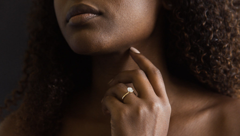 woman wearing yellow gold ring engagement ring with hand near face