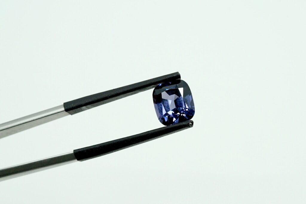 tweezers holding loose spinel engagement ring gemstone