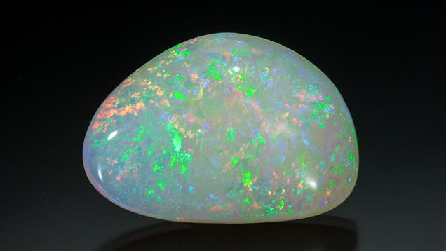 white opal with green spots on black background