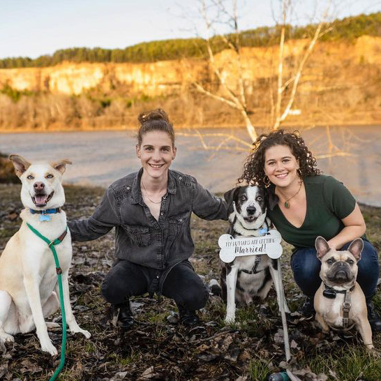 couple posing with three dogs