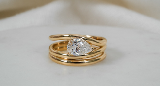 http://custom%20three%20strand%20engagement%20ring%20in%20yellow%20gold%20with%20pear%20diamond%20set%20east%20west