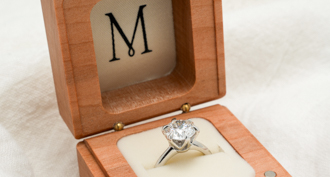 http://white%20gold%20round%20diamond%20engagement%20ring%20in%20wooden%20ring%20box%20featuring%20M%20logo
