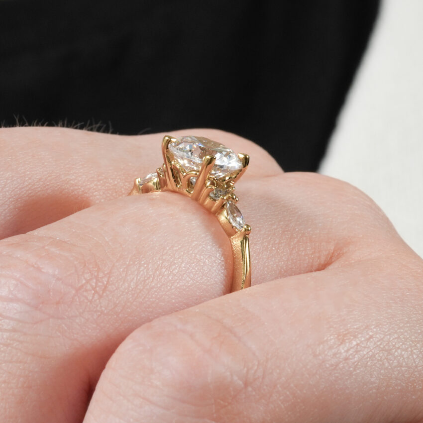 Angle view of marquise and round cluster engagement ring in lifestyle