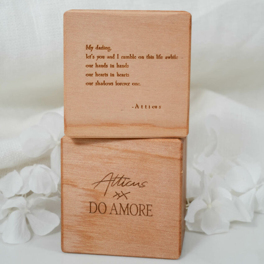 lifestyle image of wooden ring boxes stacked with you and i poem engraved