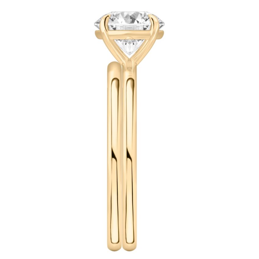 Side view of four prong round cut diamond delicate solitaire engagement ring set yellow gold