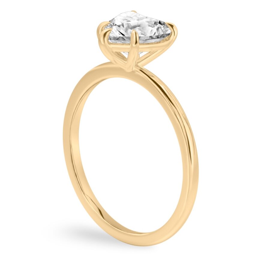 Angle view of heart shape diamond delicate solitaire engagement ring yellow gold