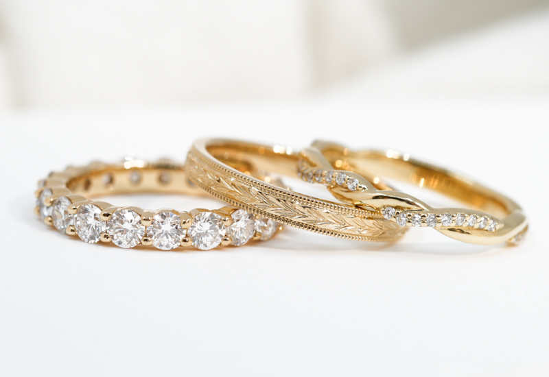 three yellow gold womens wedding bands stacked on a white surface