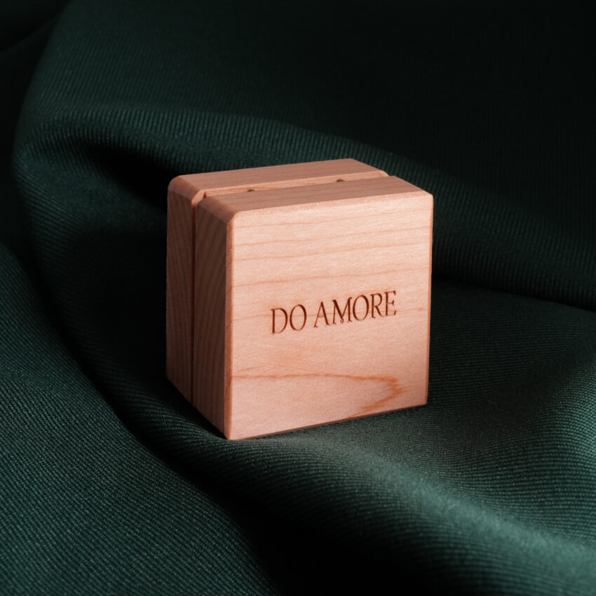 light colored wooden ring box with Do Amore logo on green backdrop