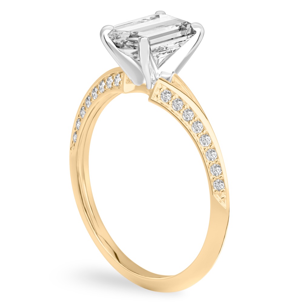 Angle view of emerald cut diamond split shank knife edge engagement ring in yellow gold