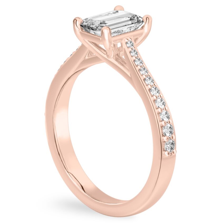 Angle view of emerald cut diamond tapered engagement ring in rose gold
