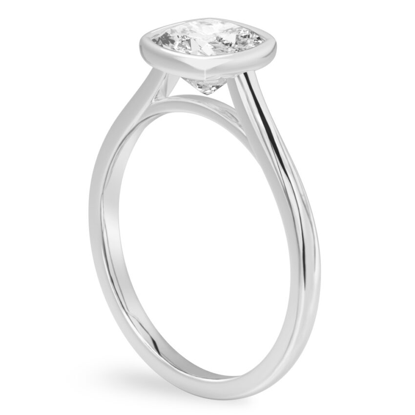 Angle view of cushion cut diamond bezel engagement ring in white gold
