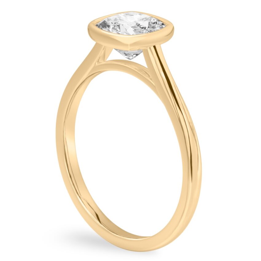 Angle view of cushion cut diamond bezel engagement ring in yellow gold
