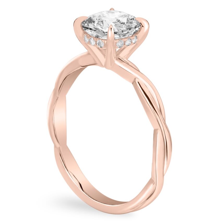 Angle view of cushion cut diamond twisted hidden halo engagement ring in rose gold