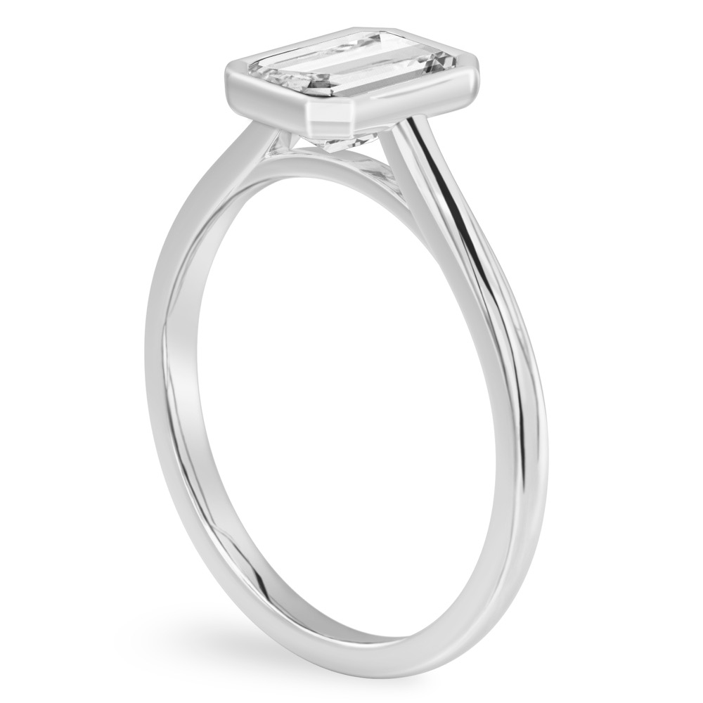 Angle view of emerald cut diamond bezel engagement ring in white gold
