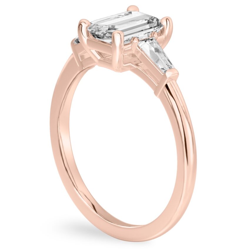 Angle view of emerald cut diamond tapered baguette engagement ring in rose gold
