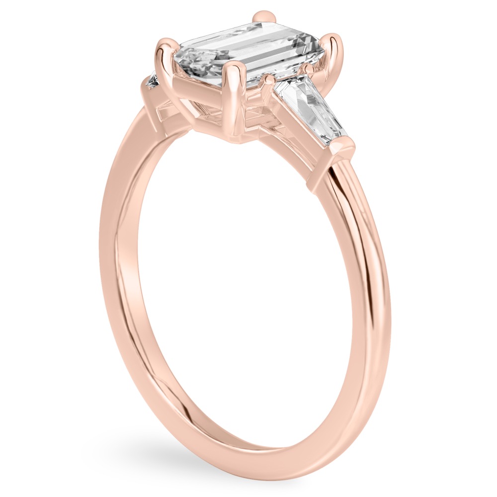 Angle view of emerald cut diamond tapered baguette engagement ring in rose gold