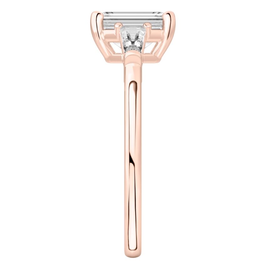 Side view of emerald cut diamond tapered baguette engagement ring in rose gold