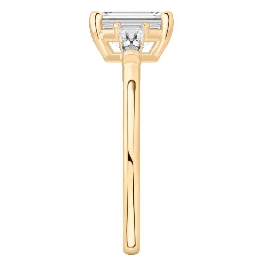 Side view of emerald cut diamond tapered baguette engagement ring in yellow gold