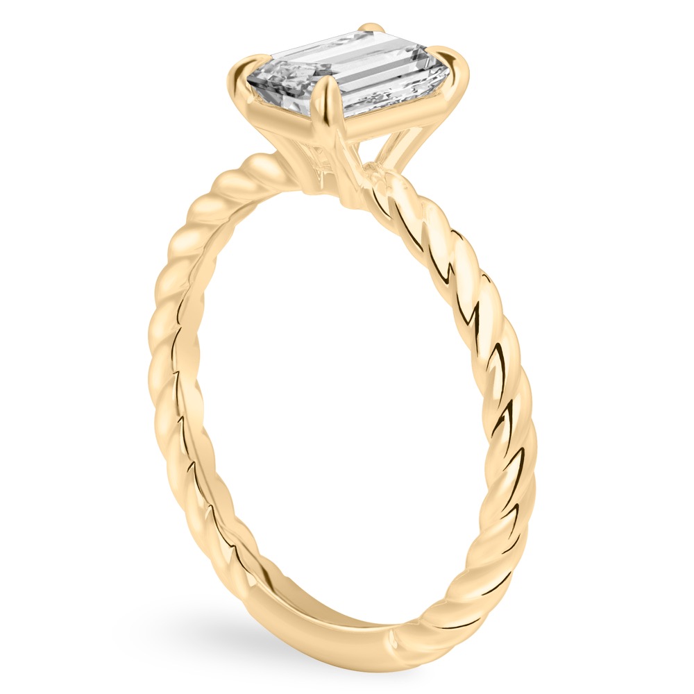 Angle view of emerald cut diamond twisted rope engagement ring in yellow gold