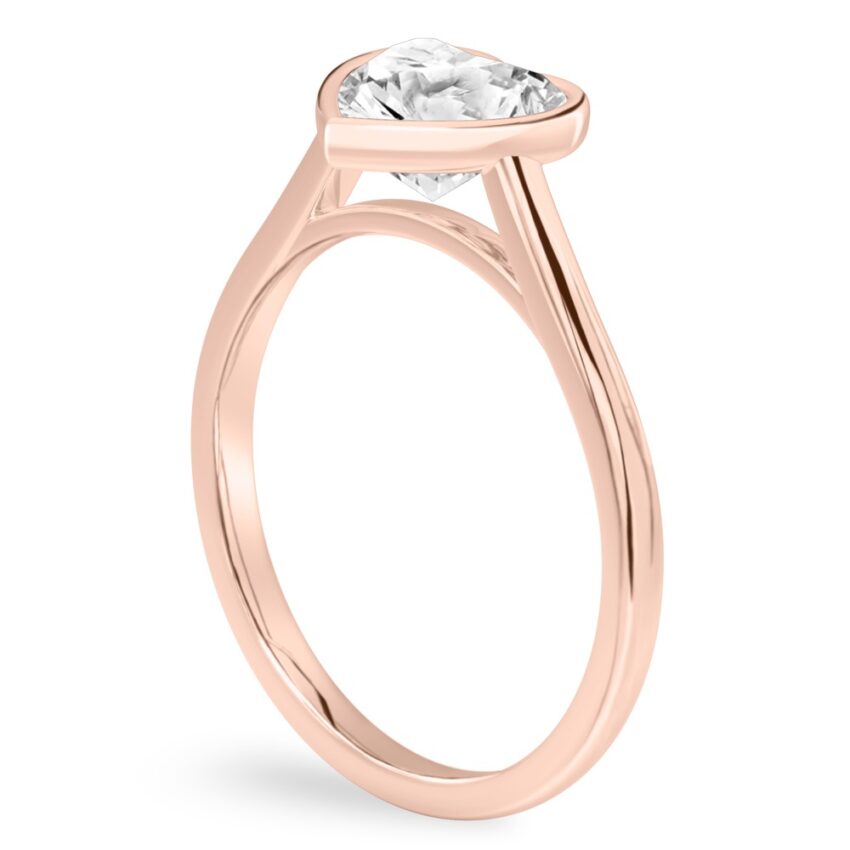 Angle view of heart shape diamond bezel engagement ring in rose gold