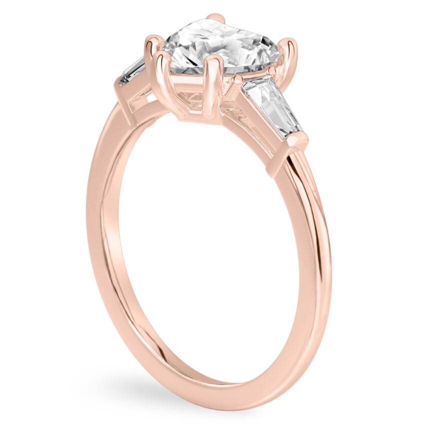 Angle view of heart shape diamond tapered baguette engagement ring in rose gold