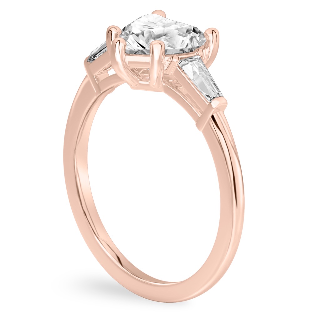 Angle view of heart shape diamond tapered baguette engagement ring in rose gold
