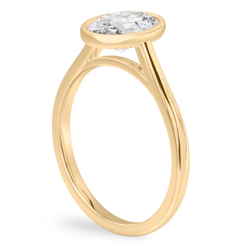 Angle view of oval shape diamond bezel engagement ring in yellow gold