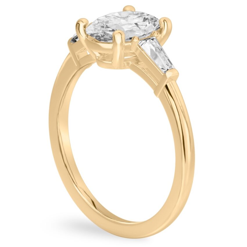 Angle view of oval shape diamond tapered baguette engagement ring in yellow gold