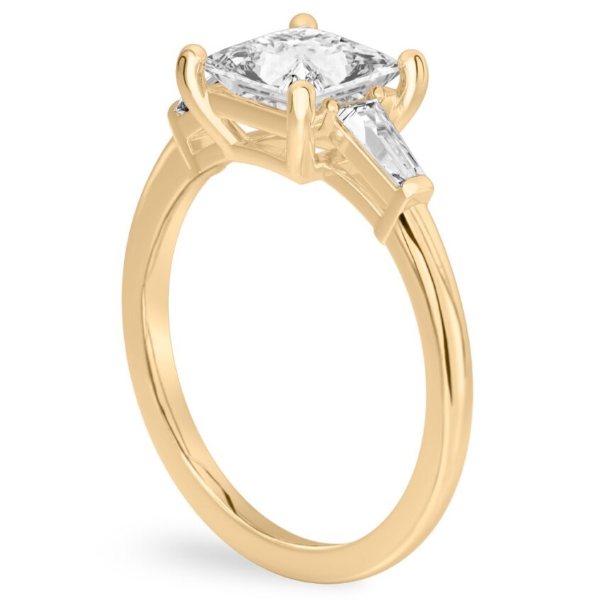 Angle view of princess cut diamond tapered baguette engagement ring in yellow gold