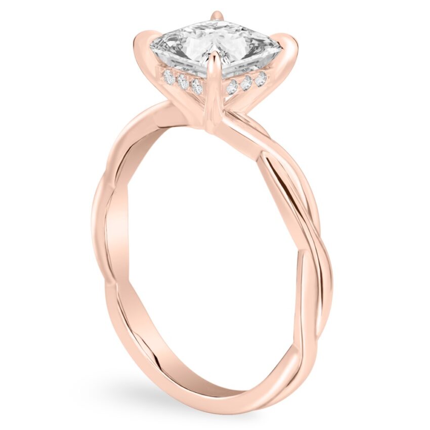 Angle view of princess cut diamond twisted hidden halo engagement ring in rose gold