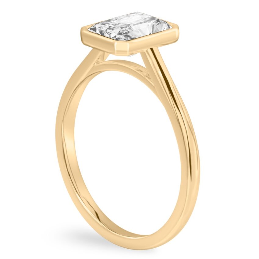 Angle view of radiant cut diamond bezel engagement ring in yellow gold