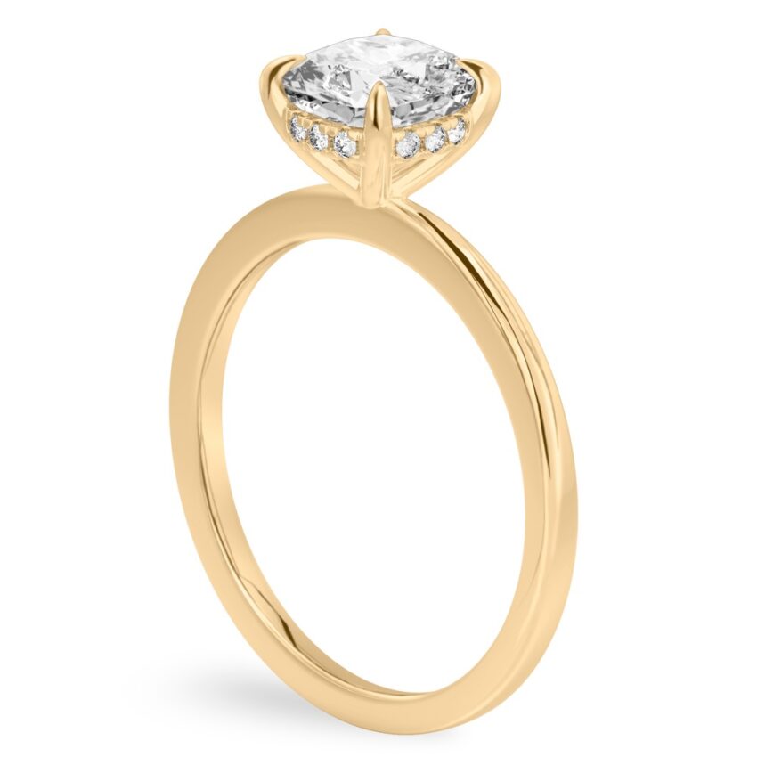 Angle view of cushion cut diamond hidden halo engagement ring in yellow gold
