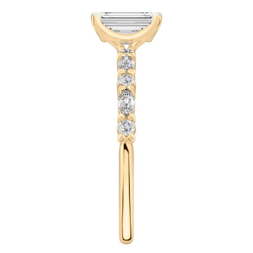 Side view of emerald cut diamond marquise and round diamond ring yellow gold
