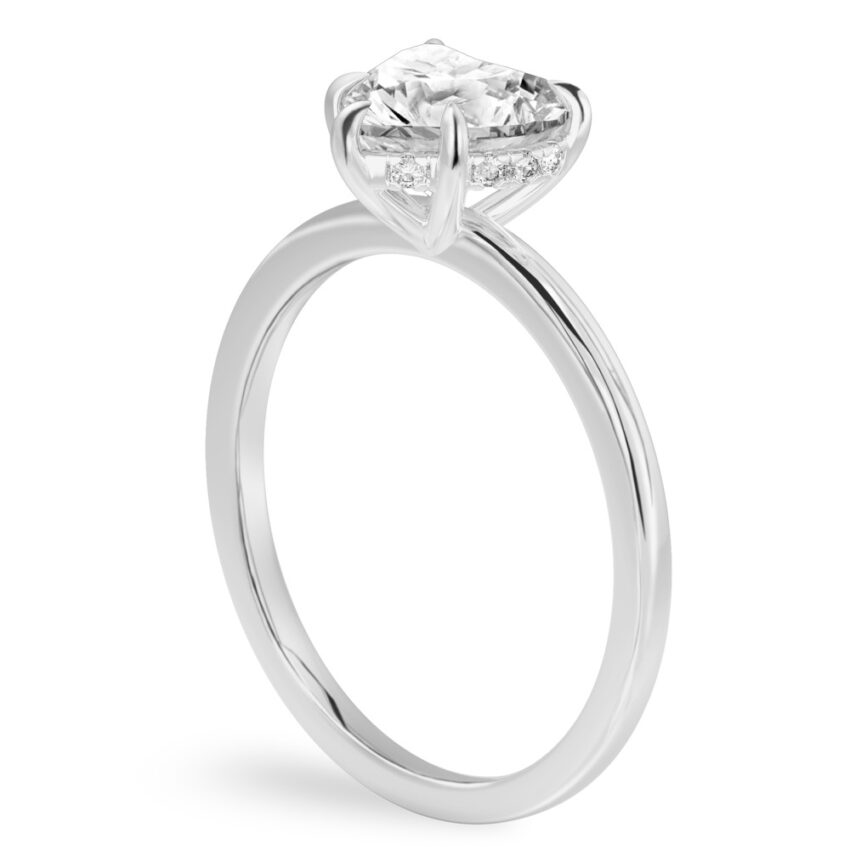Angle view of heart shape diamond ultra low hidden halo engagement ring in platinum