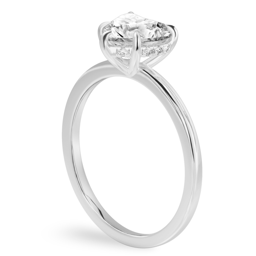 Angle view of heart shape diamond ultra low hidden halo engagement ring in platinum