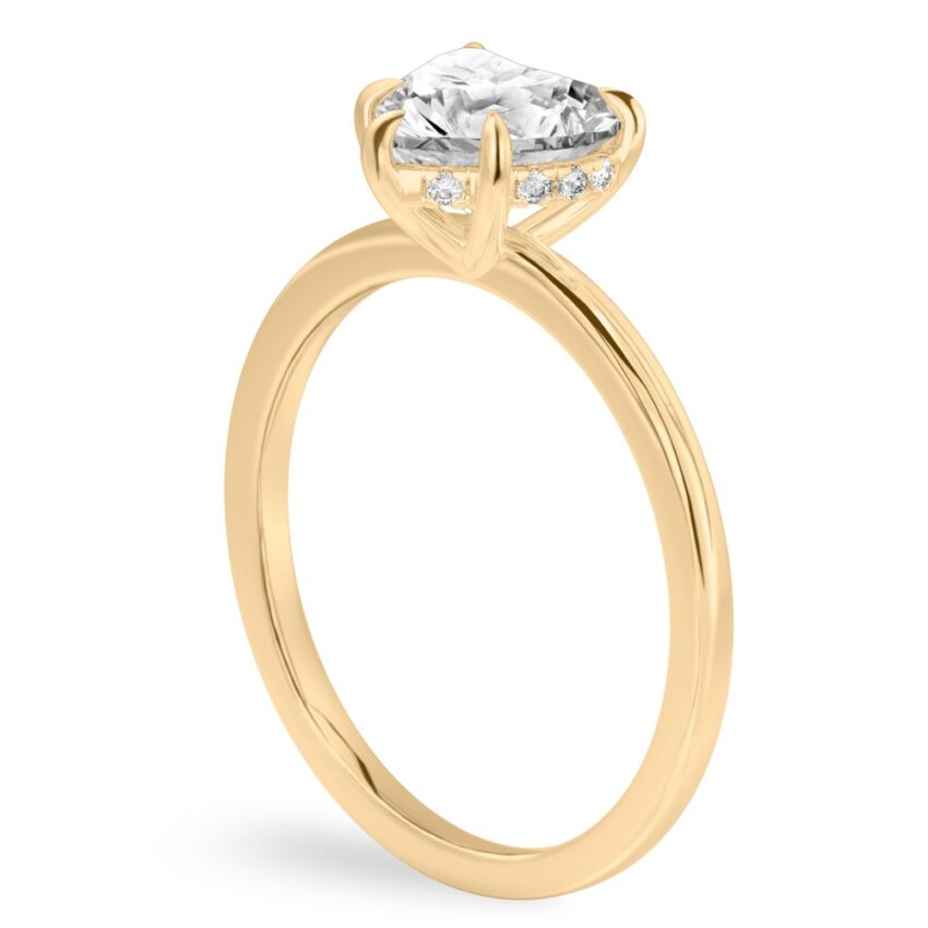 Angle view of heart shape diamond ultra low hidden halo engagement ring in yellow gold