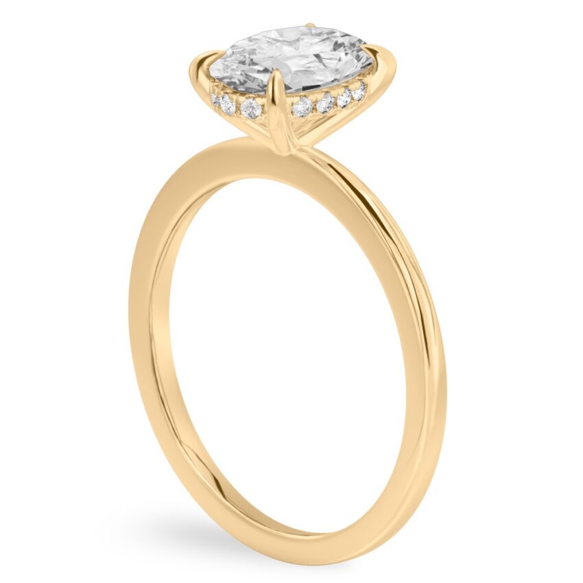 Angle view of oval shape diamond flush hidden halo engagement ring in yellow gold