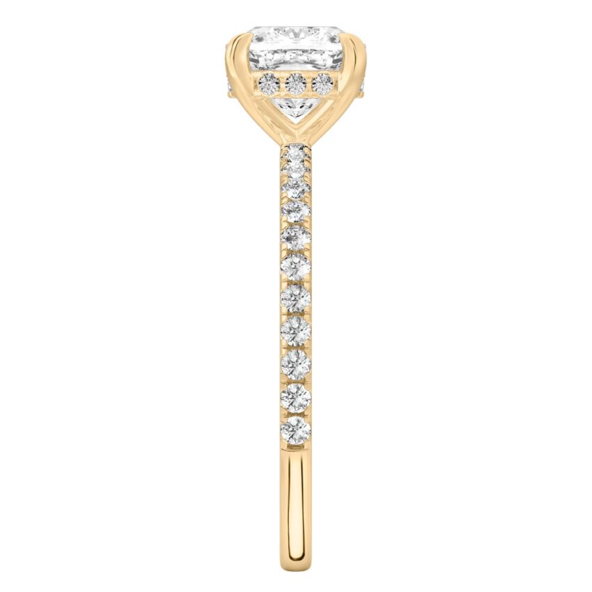 Side view of cushion cut diamond delicate pave hidden halo engagement ring in yellow gold