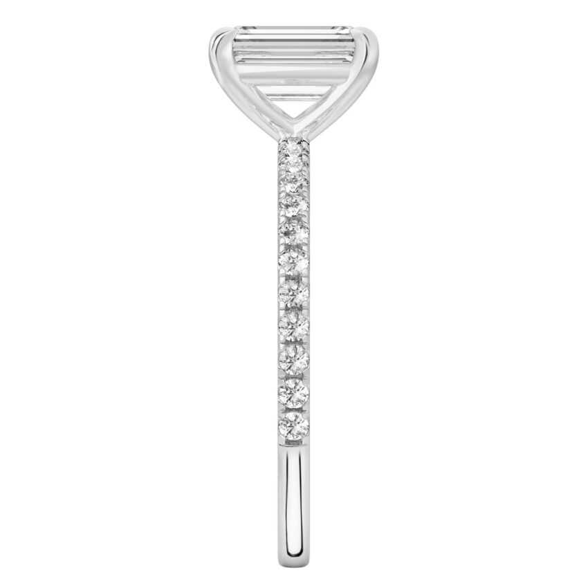 Side view of emerald cut diamond delicate pave engagement ring in platinum