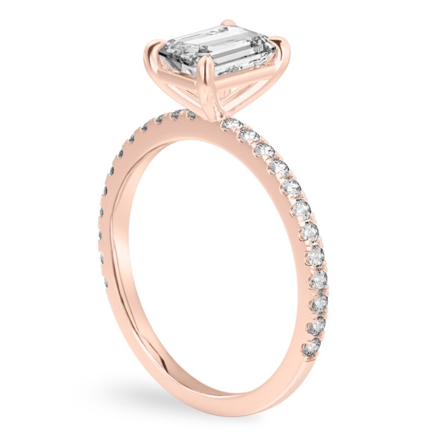 Angle view of emerald cut diamond delicate pave engagement ring in rose gold