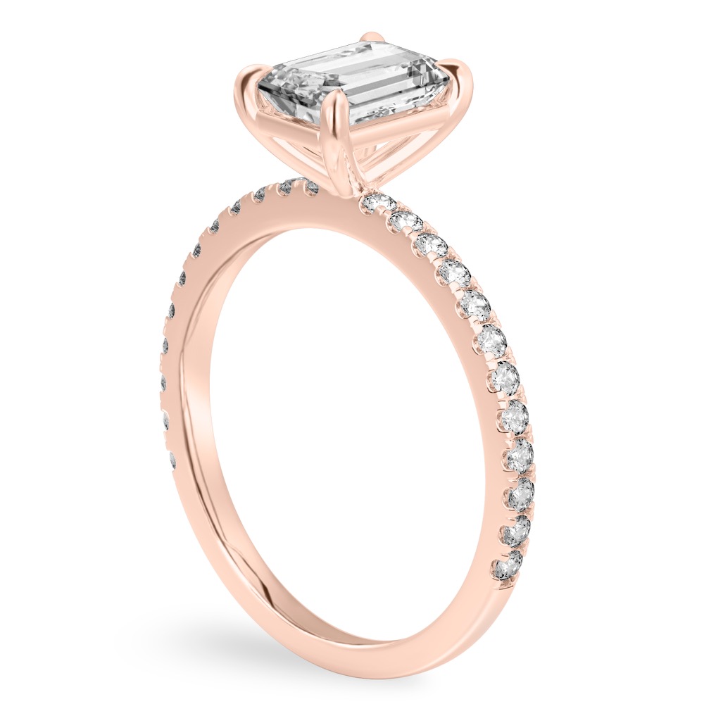 Angle view of emerald cut diamond delicate pave engagement ring in rose gold