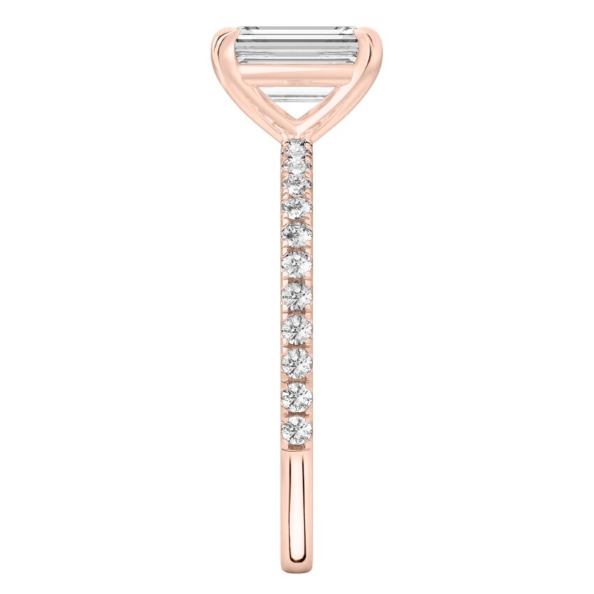 Side view of emerald cut diamond delicate pave engagement ring in rose gold