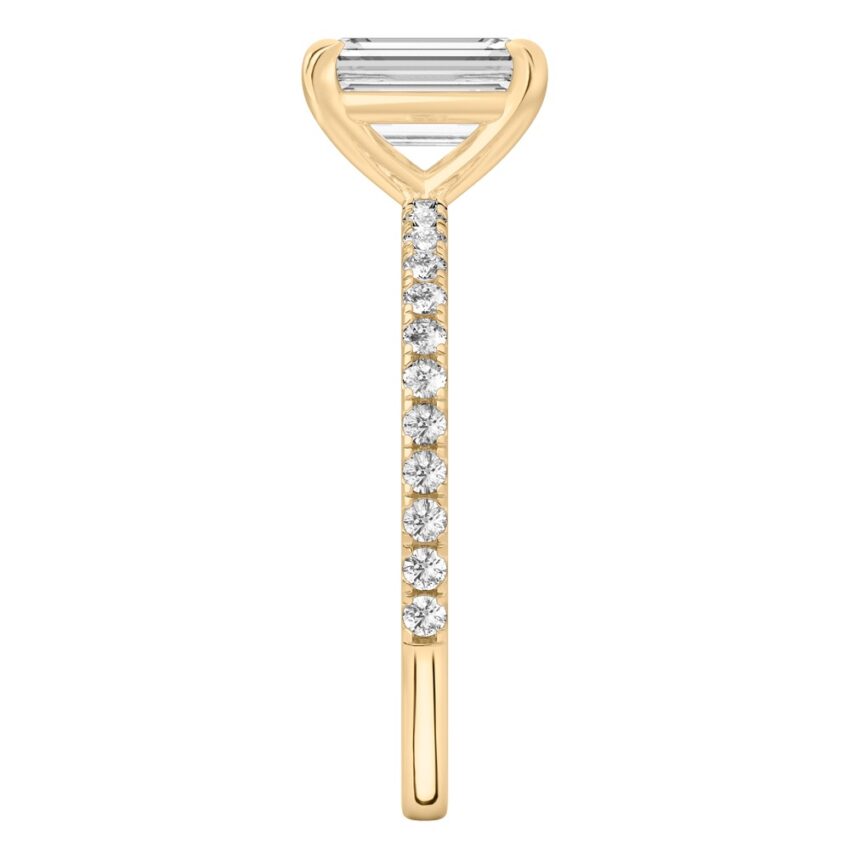 Side view of emerald cut diamond delicate pave engagement ring in yellow gold